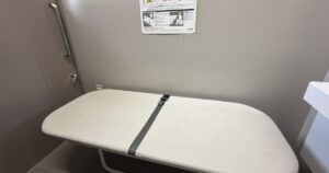都立明治公園のトイレに設置されたユニバーサルシート。折りたたみ式の白い介助用ベッド